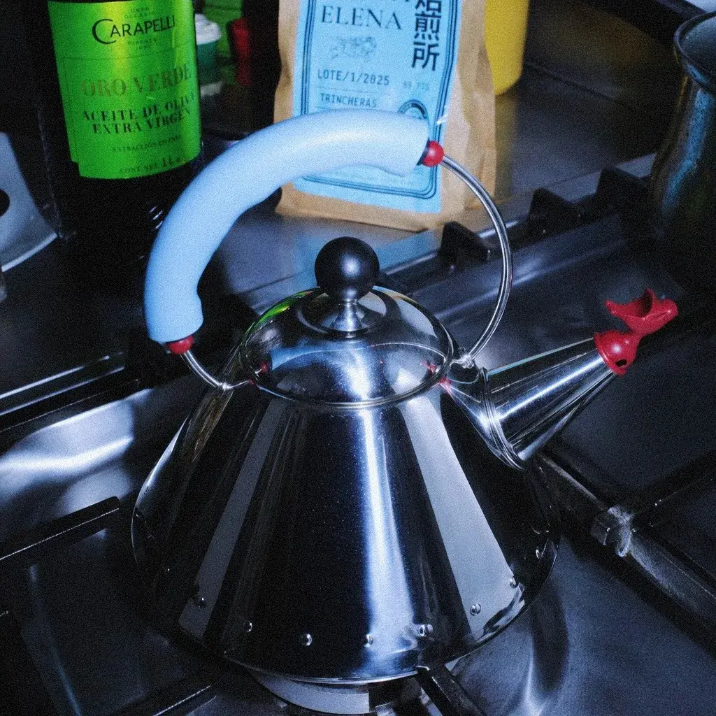 Kettle Alessi 9093 sobre la estufa, con el silbato de pajaro rojo en el pico