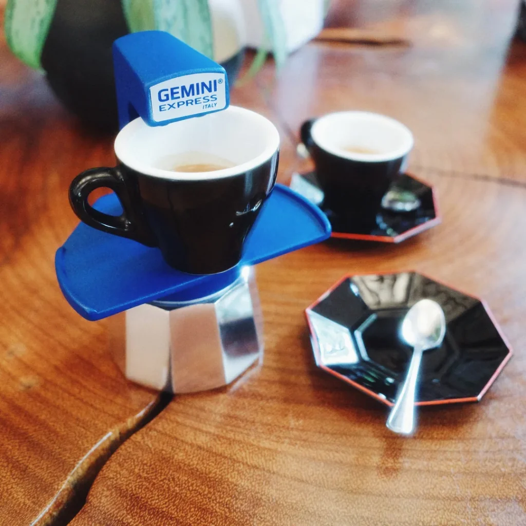 Cafetera Gemini Express azul con un espresso servido sobre una mesa de madera