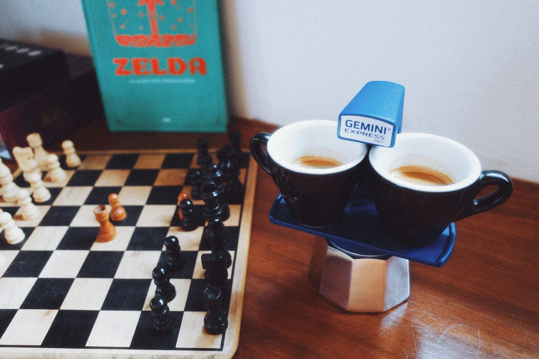 Cafetera Gemini Express azul con dos espressos servidos junto a un tablero de ajedrez
